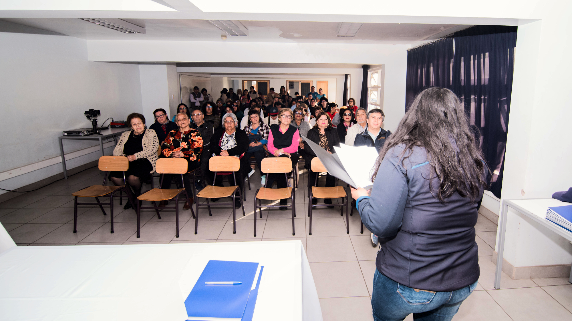 Mujer leyendo ante público en sala