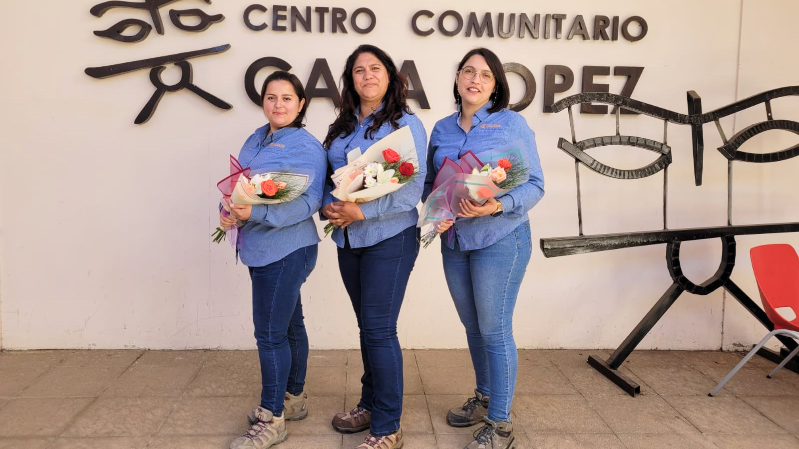 Tres mujeres con ramos frente a centro comunitario