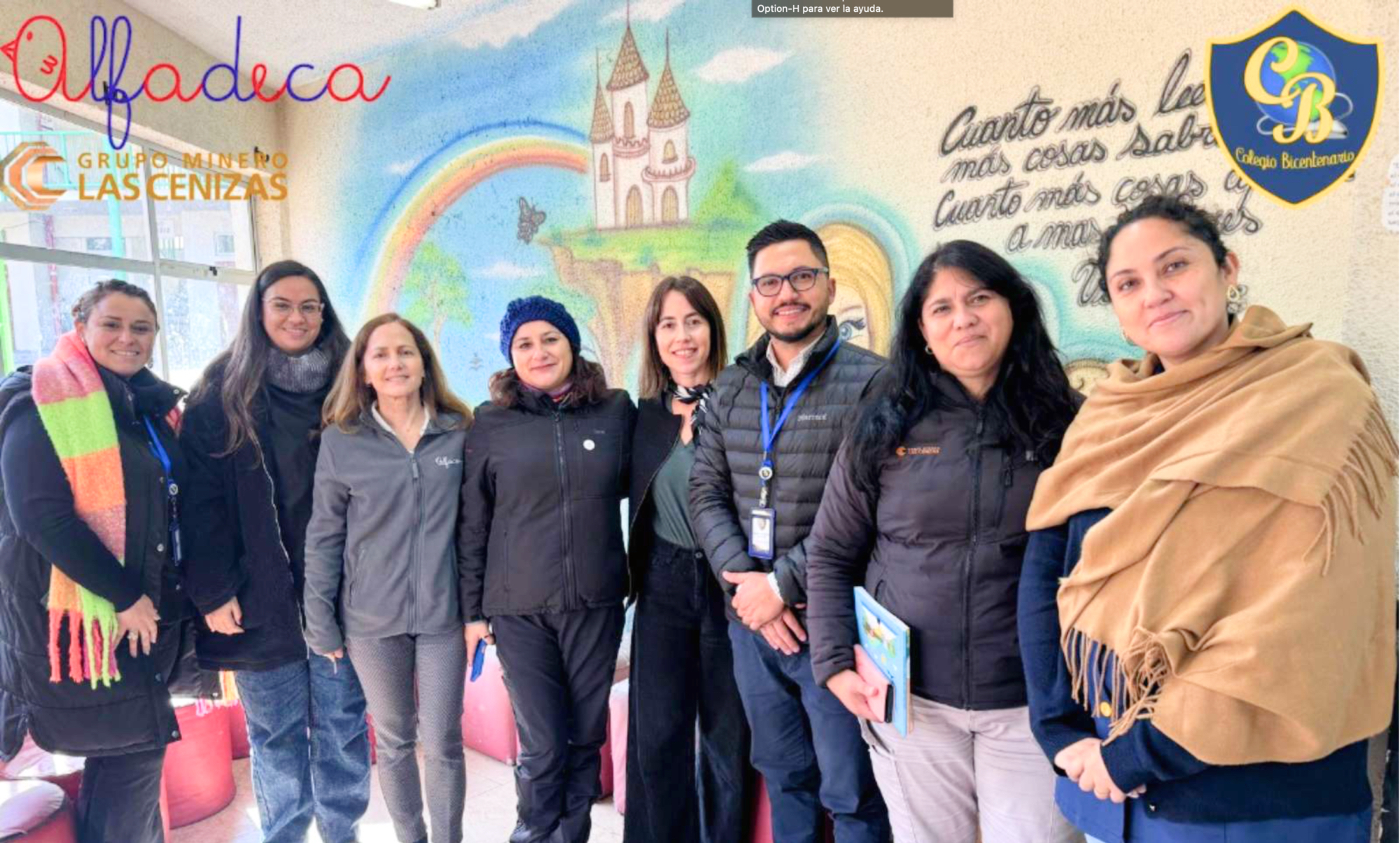 Equipo posando frente a mural escolar colorido