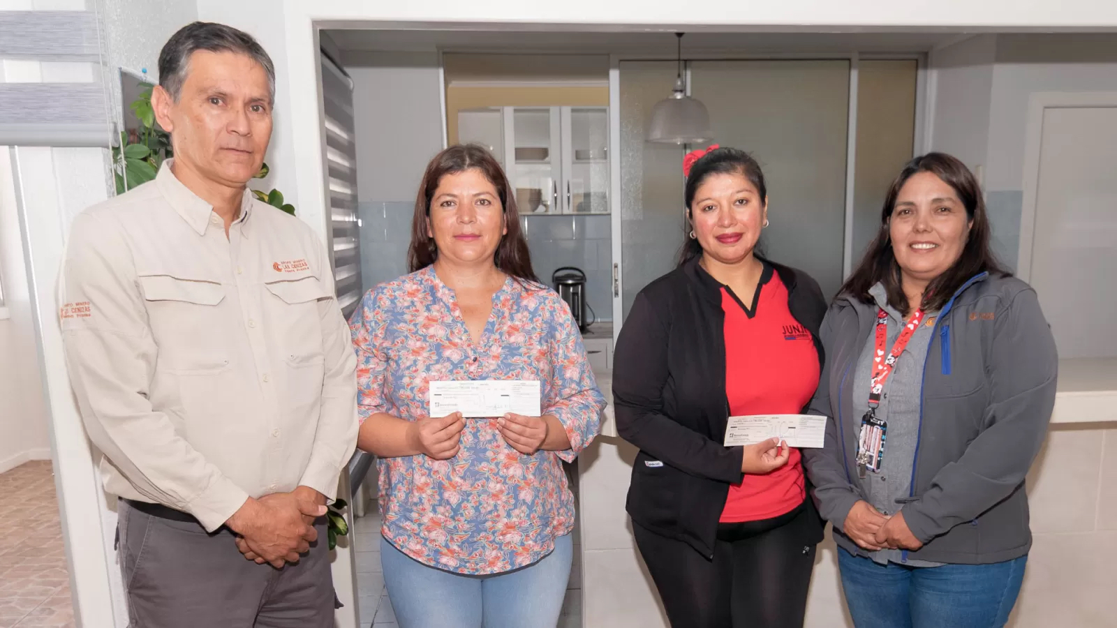 Cuatro adultos posan con cheques en interior