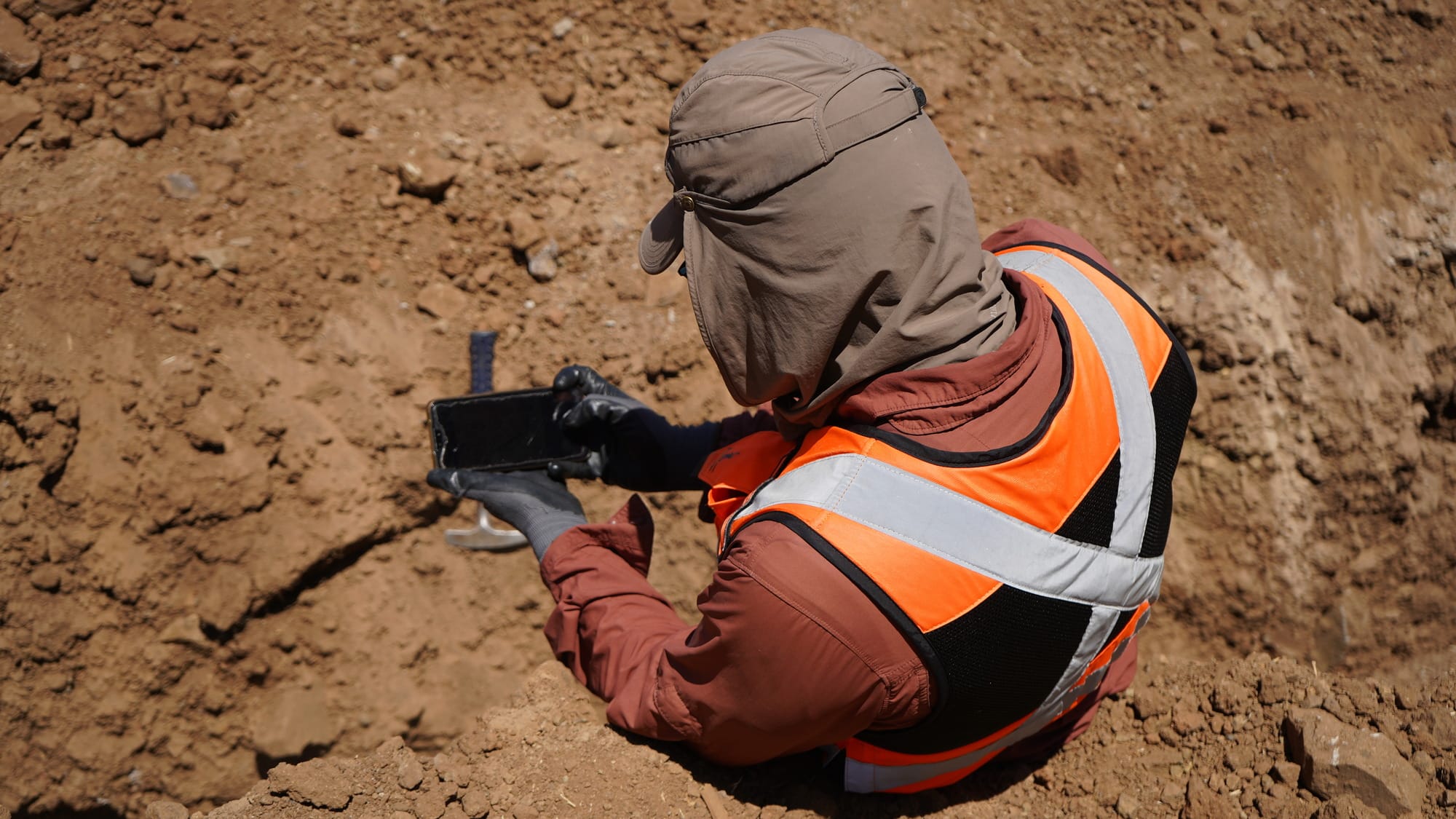 Trabajador con chaleco reflectante usando móvil en excavación