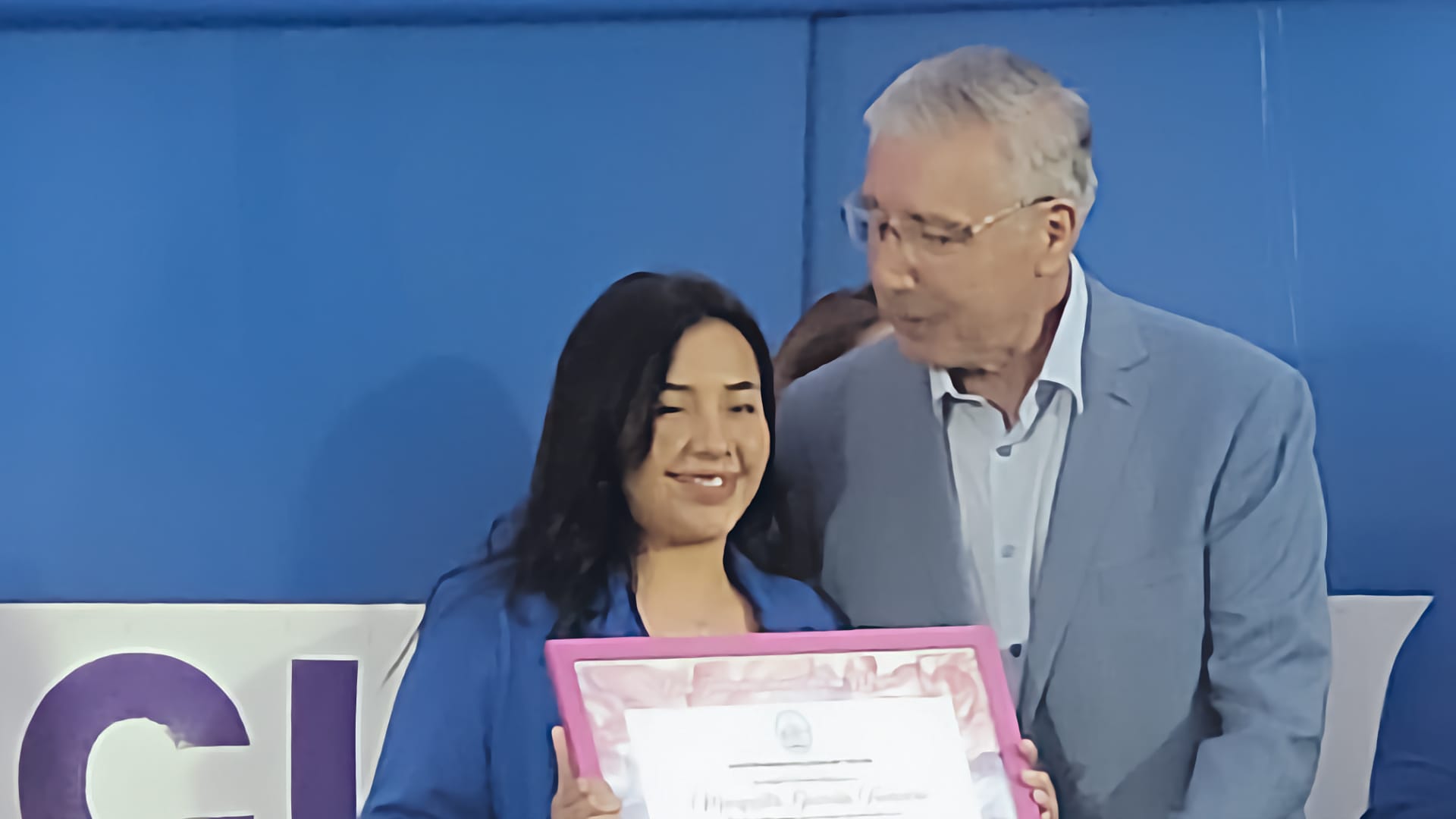 Mujer recibe certificado en evento oficial