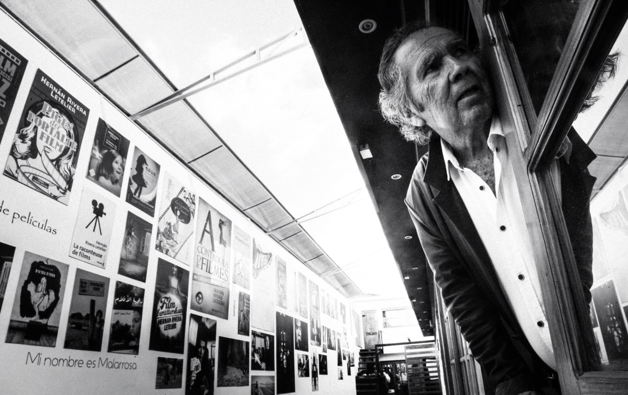 Hombre mayor asomado junto a carteles de cine