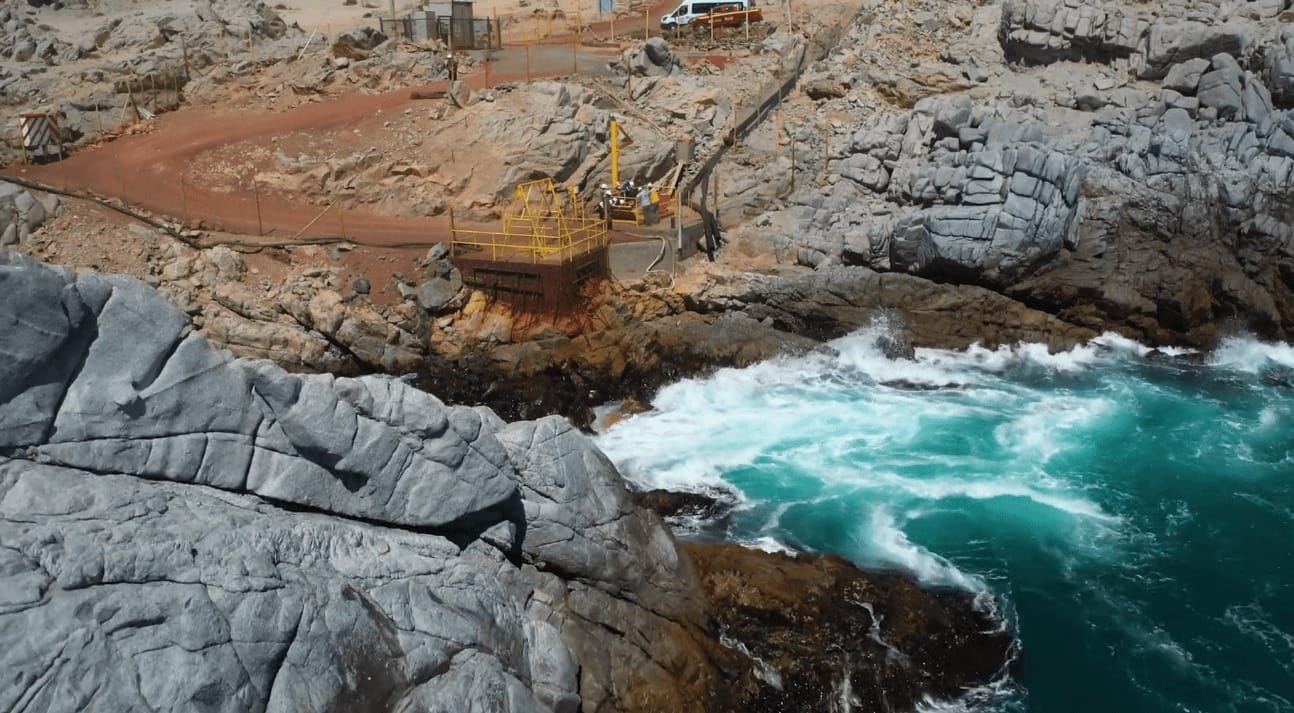 Plataforma industrial en costa rocosa con olas