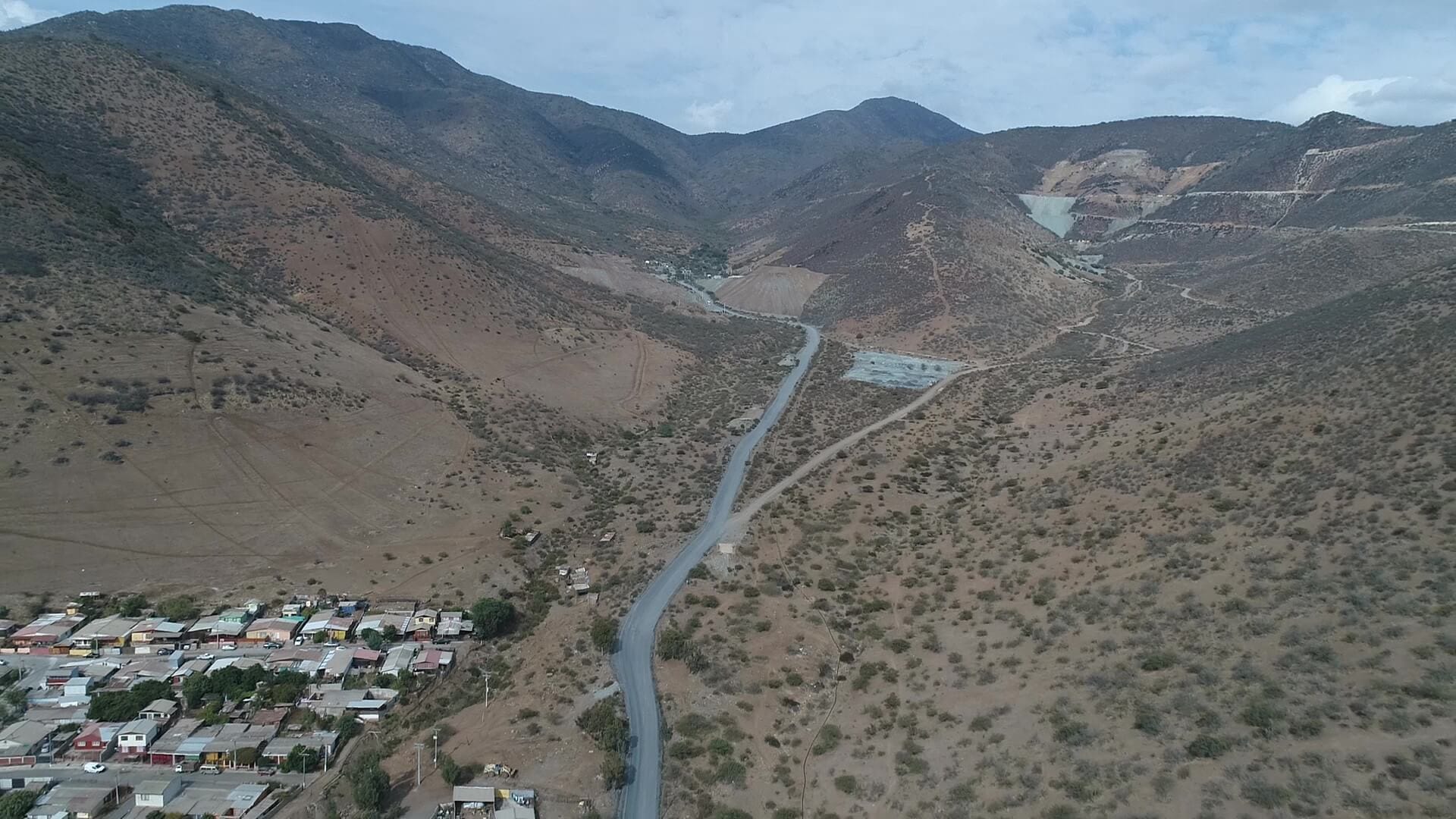 Carretera sinuosa entre montañas áridas y pueblo