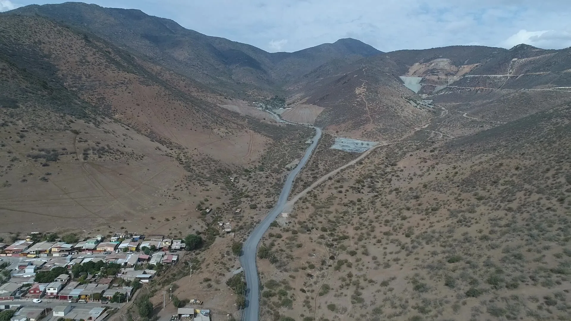 Carretera sinuosa entre montañas áridas y pueblo