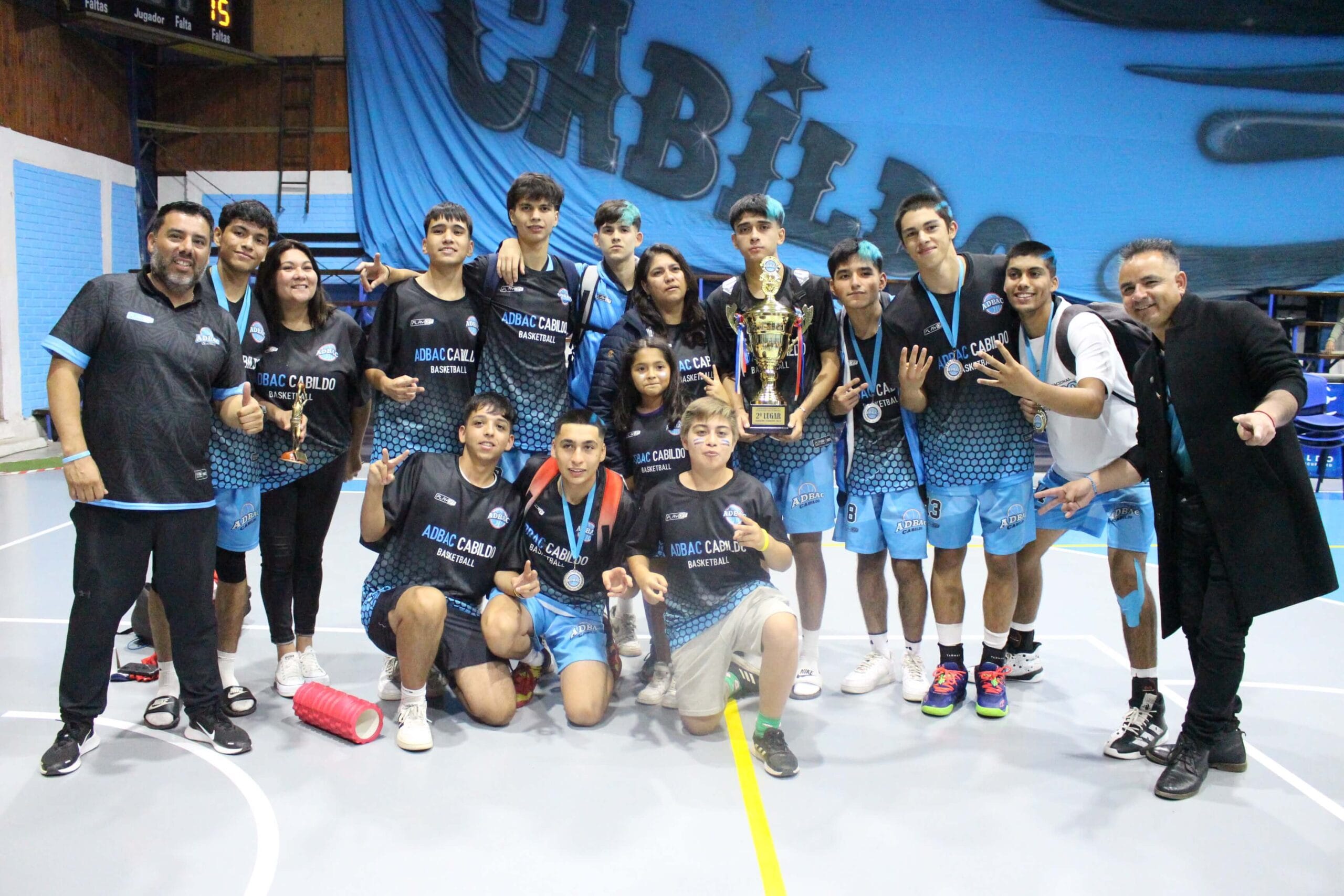 Equipo juvenil de baloncesto con trofeo en pista