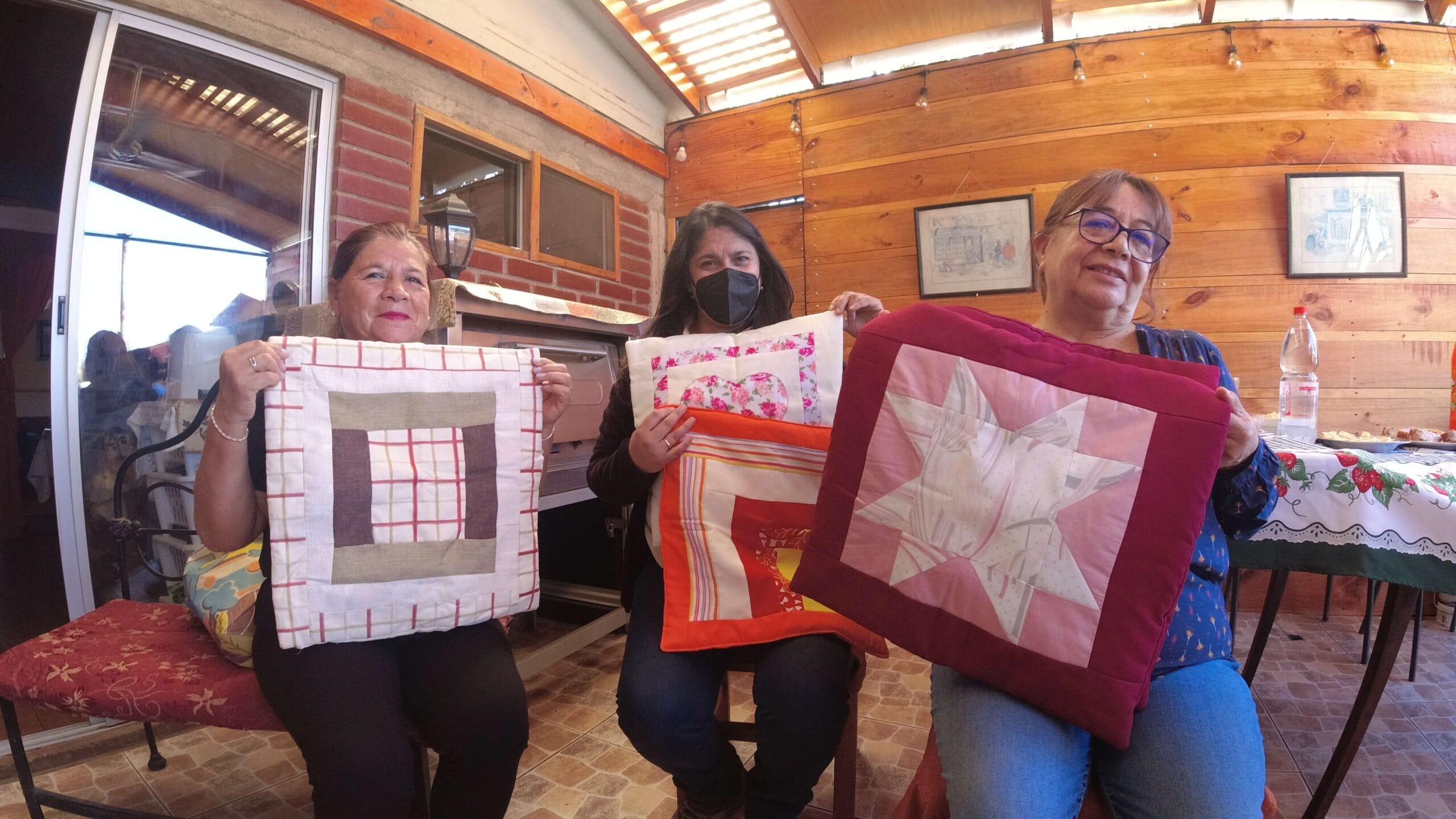 Tres mujeres muestran cojines de patchwork artesanales