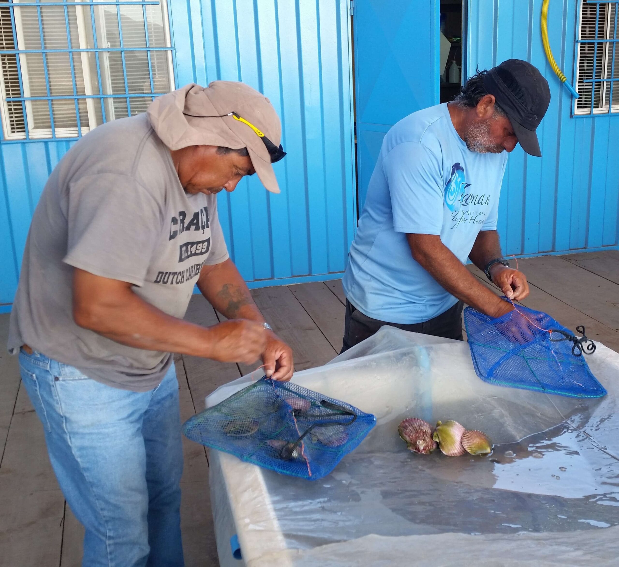 Dos hombres preparando marisco en bolsas de red