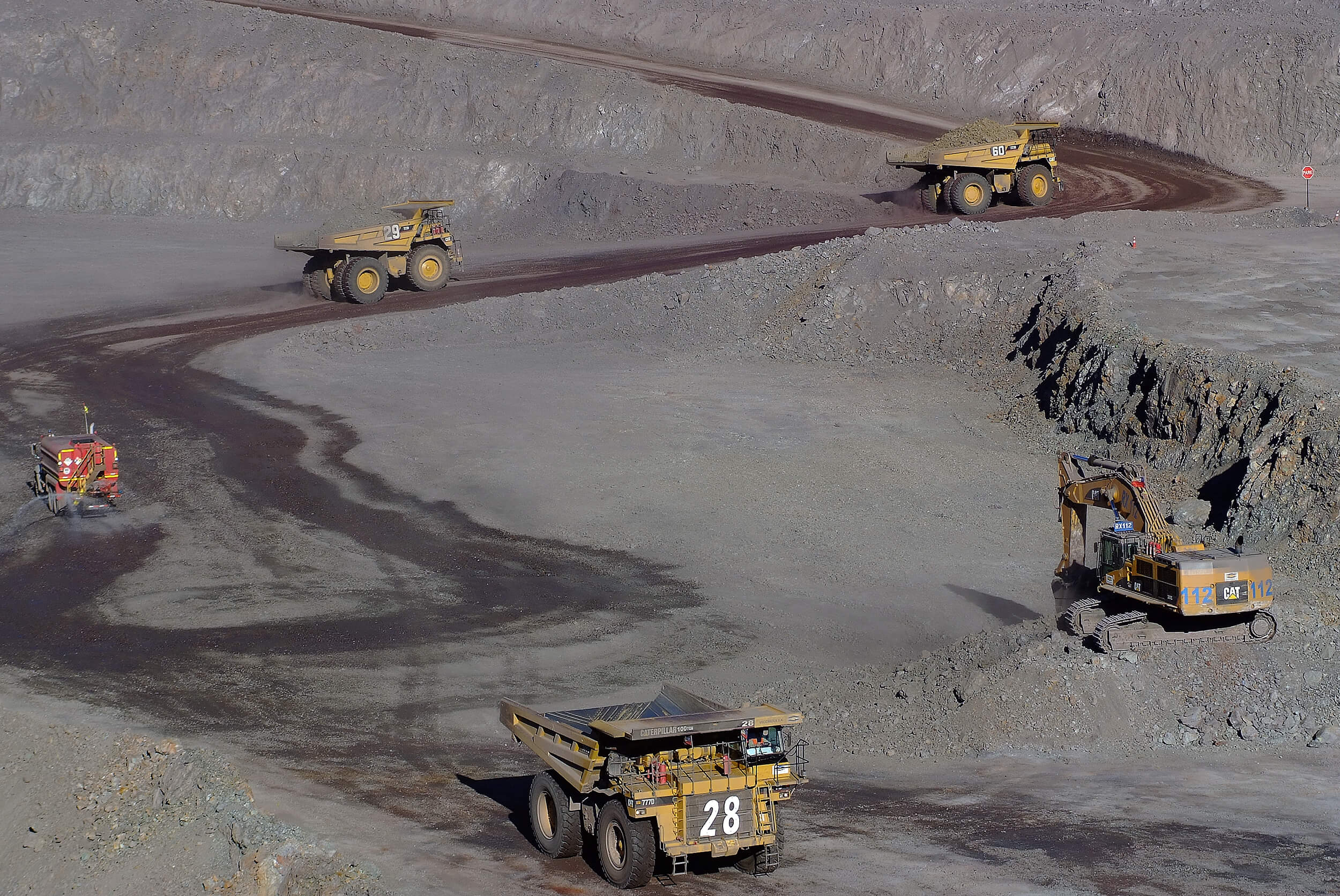 Camiones mineros y excavadora en mina a cielo abierto