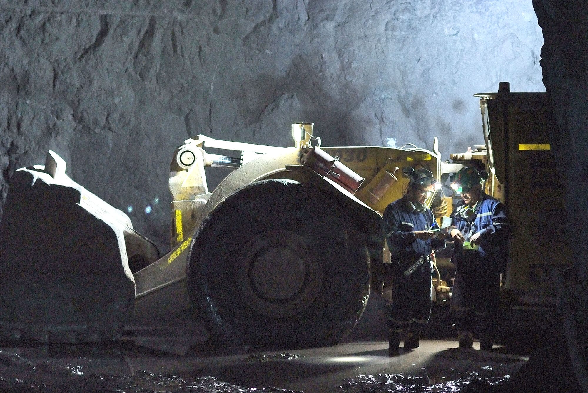 Mineros junto a maquinaria pesada en mina subterránea