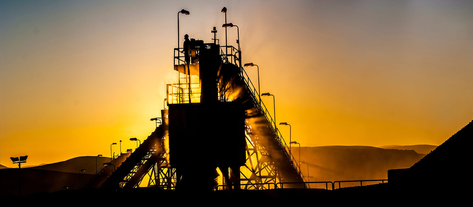 Planta industrial al atardecer con silueta de trabajador