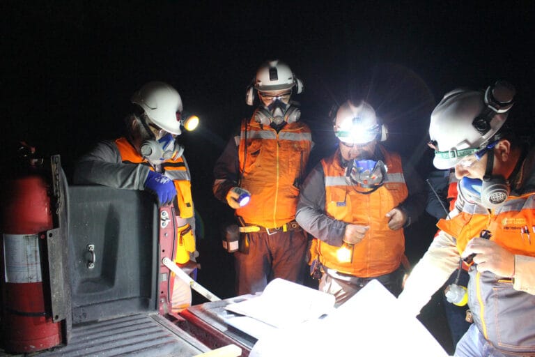 Trabajadores con cascos revisando planos en mina