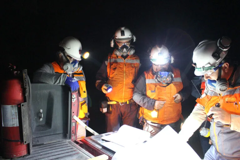 Trabajadores con cascos revisando planos en mina