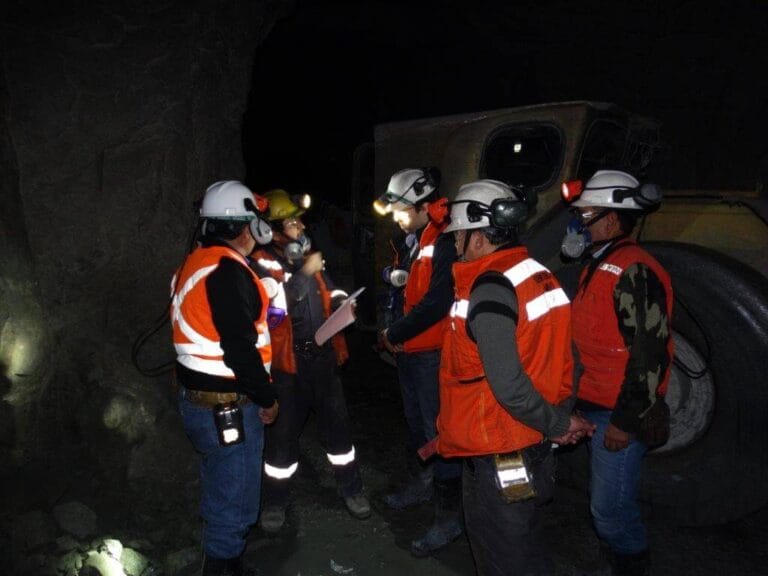 Mineros con cascos y linternas en mina subterránea