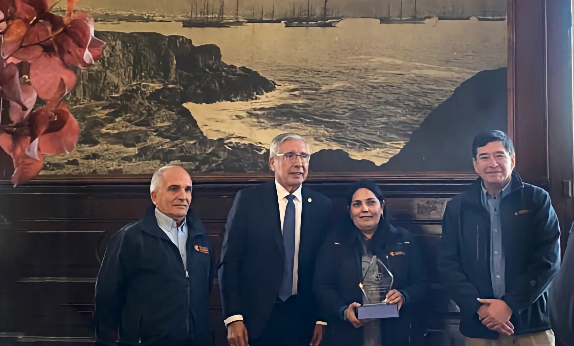 Cuatro personas posan con premio en salón elegante