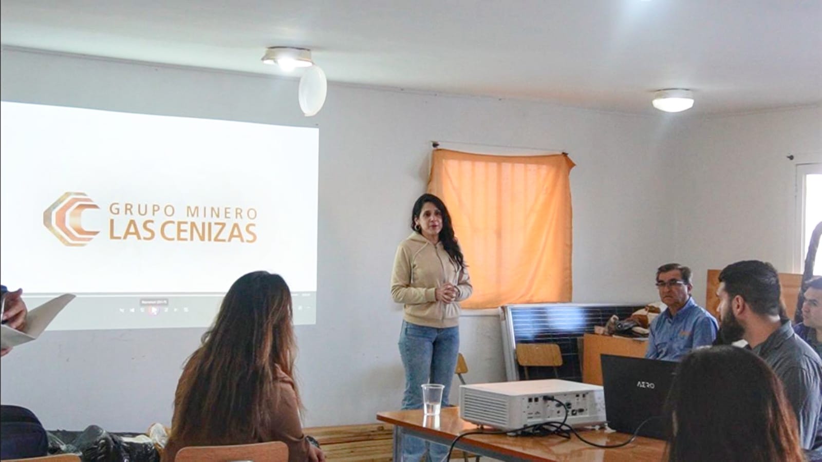 Mujer presenta ante equipo con proyector corporativo